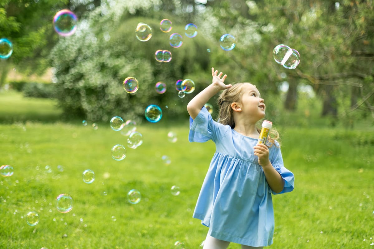 Hire bubble machine — young girl playing with bubbles in vibrant park se for parties and events in Johannesburg, Sandton and Randburg
