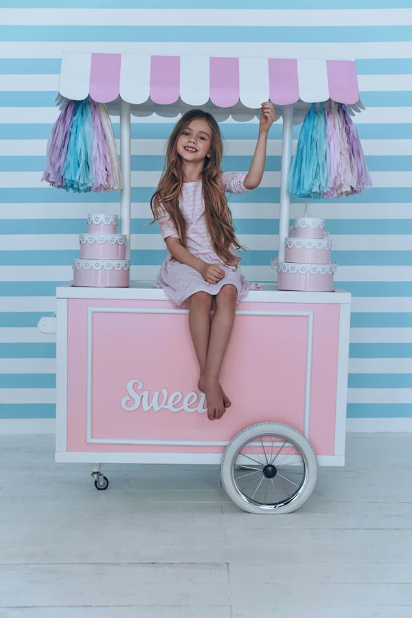 Hire candy cart — cheerful girl sits atop pink dessert cart for parties and events in Johannesburg, Sandton and Randburg