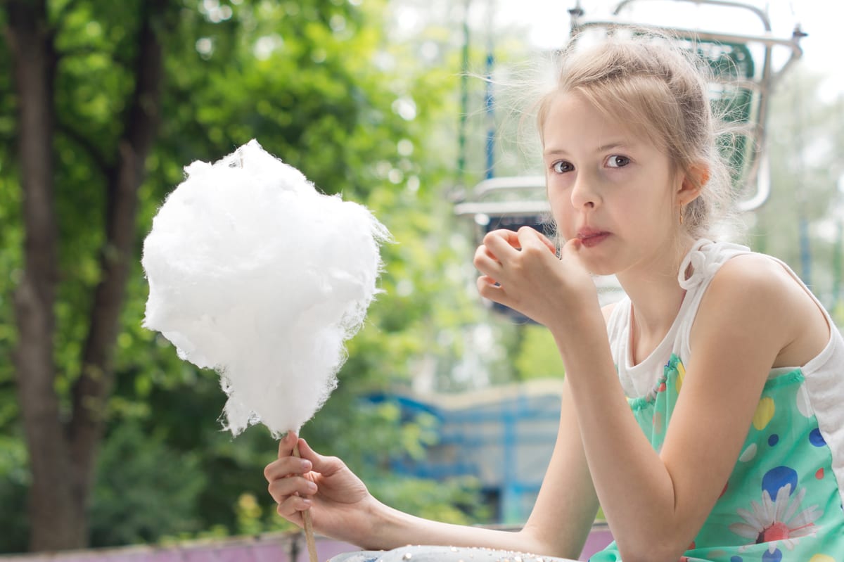 Candy Floss Machine hire — blonde girl enjoying cotton candy in park | Panda Party Hire Hire candy floss machine — blonde girl enjoying cotton candy in park for parties and events in Johannesburg, Sandton and Randburg