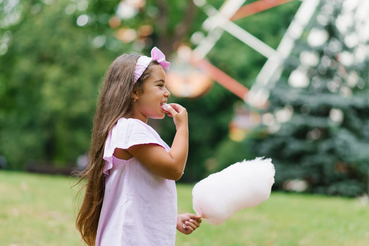Candy Floss Machine hire — funny girl in pink dress eats cotton candy in summ | Panda Party Hire Hire candy floss machine — funny girl in pink dress eats cotton candy in summ for parties and events in Johannesburg, Sandton and Randburg