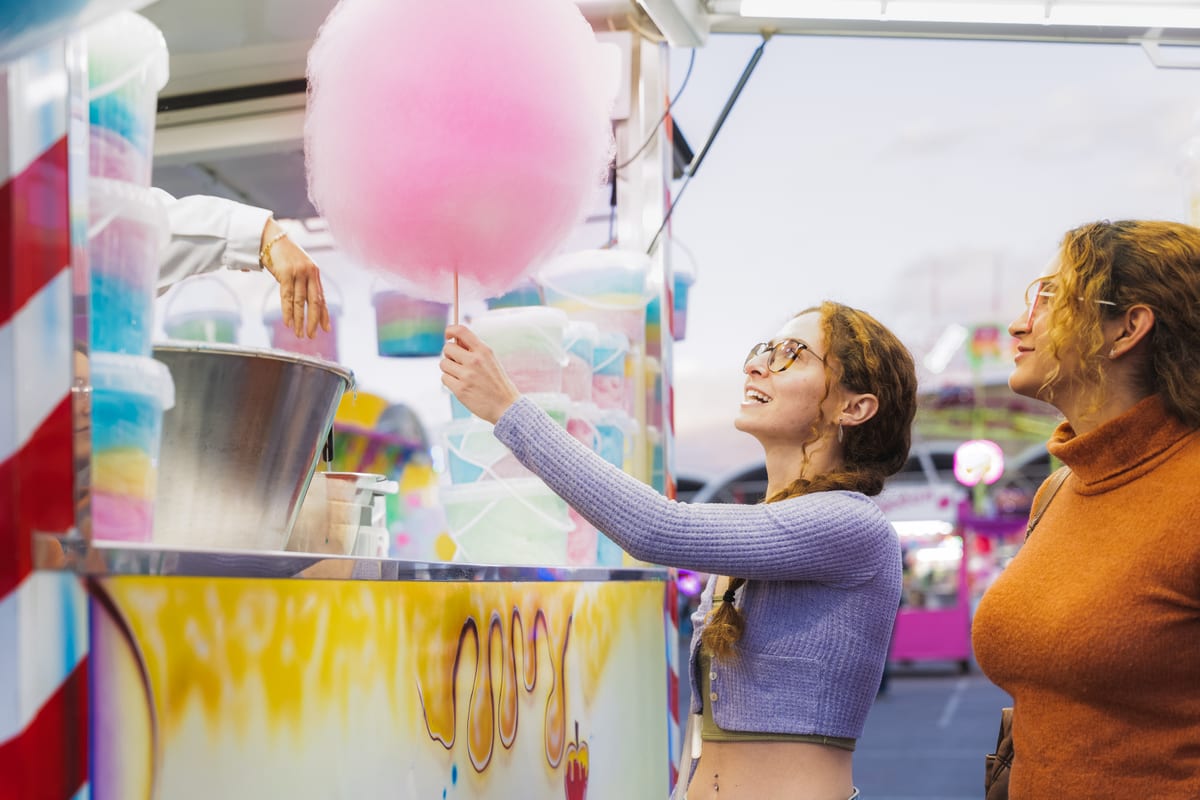 Candy Floss Machine hire — two women buying cotton candy from street vendor | Panda Party Hire Hire candy floss machine — two women buying cotton candy from street vendor for parties and events in Johannesburg, Sandton and Randburg