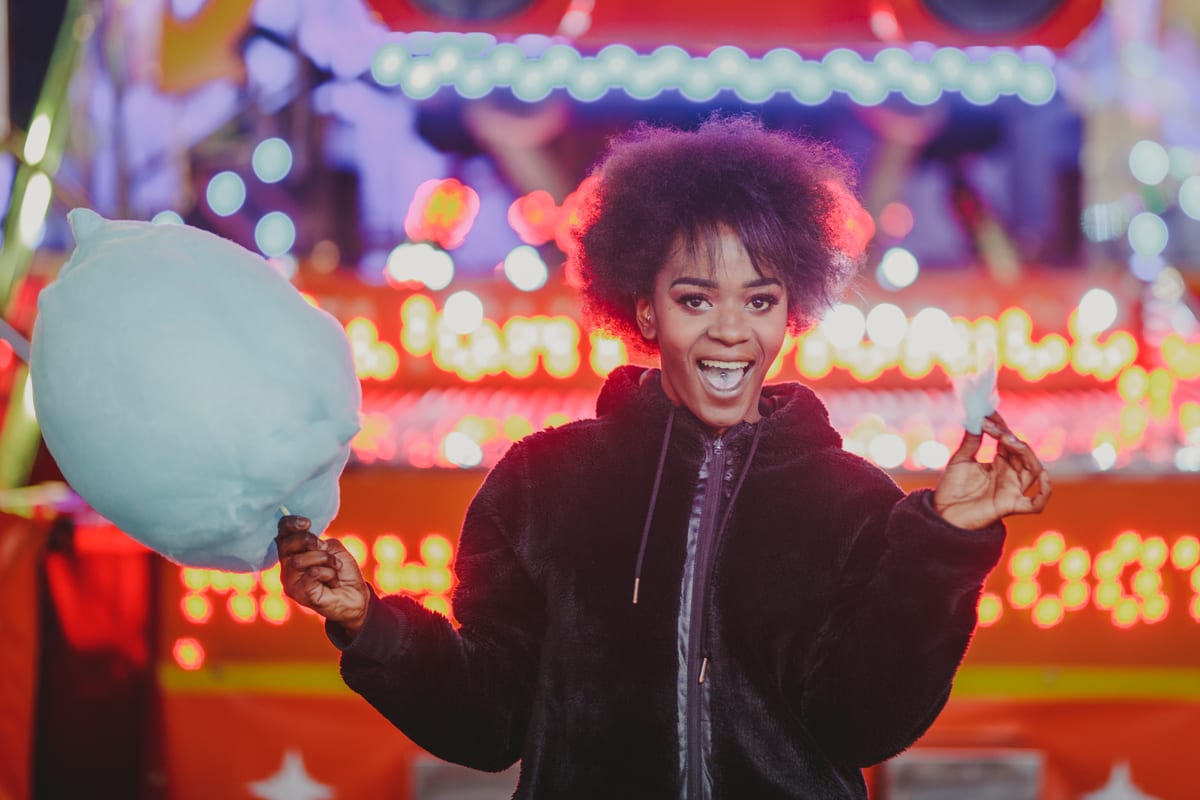 Candy Floss Machine hire — woman smiles with cotton candy at night | Panda Party Hire Hire candy floss machine — woman smiles with cotton candy at night for parties and events in Johannesburg, Sandton and Randburg