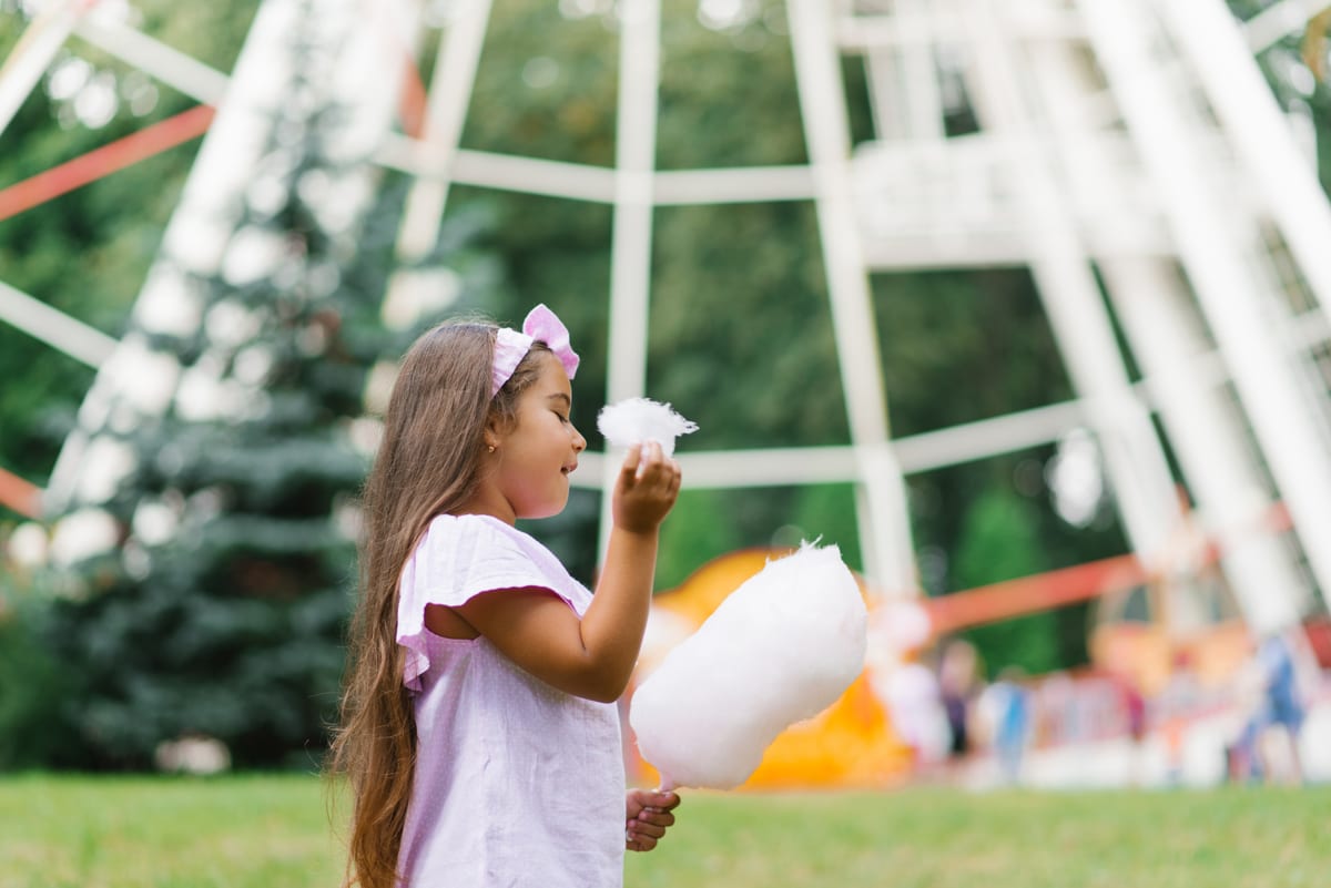 Candy Floss Machine hire — child girl in an amusement park in the summer eats | Panda Party Hire Hire candy floss machine — child girl in an amusement park in the summer eats for parties and events in Johannesburg, Sandton and Randburg