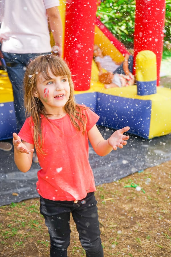 Hire jumping castle — girl playing with bubbles in front of bouncy house for parties and events in Johannesburg, Sandton and Randburg
