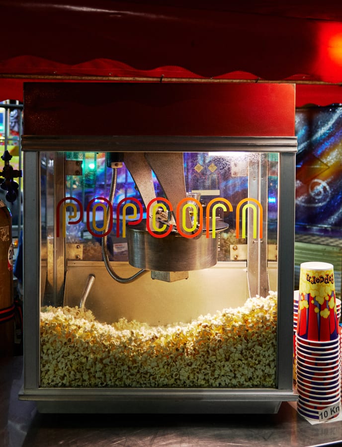 Popcorn machine hire — machine full of fresh popcorn | Panda Party Hire Hire popcorn machine — commercial popcorn machine filled with fresh buttery popcorn and stacked cups for event hire
