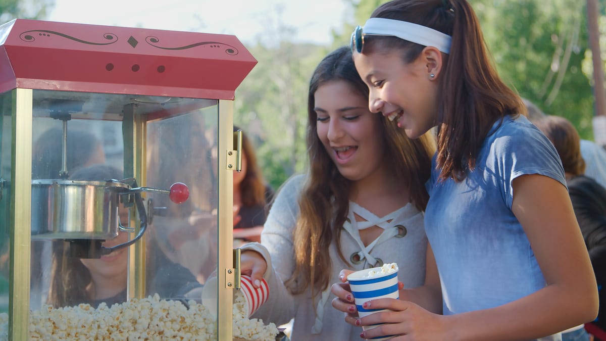 Popcorn machine hire — party kiosk popcorn station | Panda Party Hire Hire popcorn machine — guests heading to a popcorn kiosk at a fun fair style party event