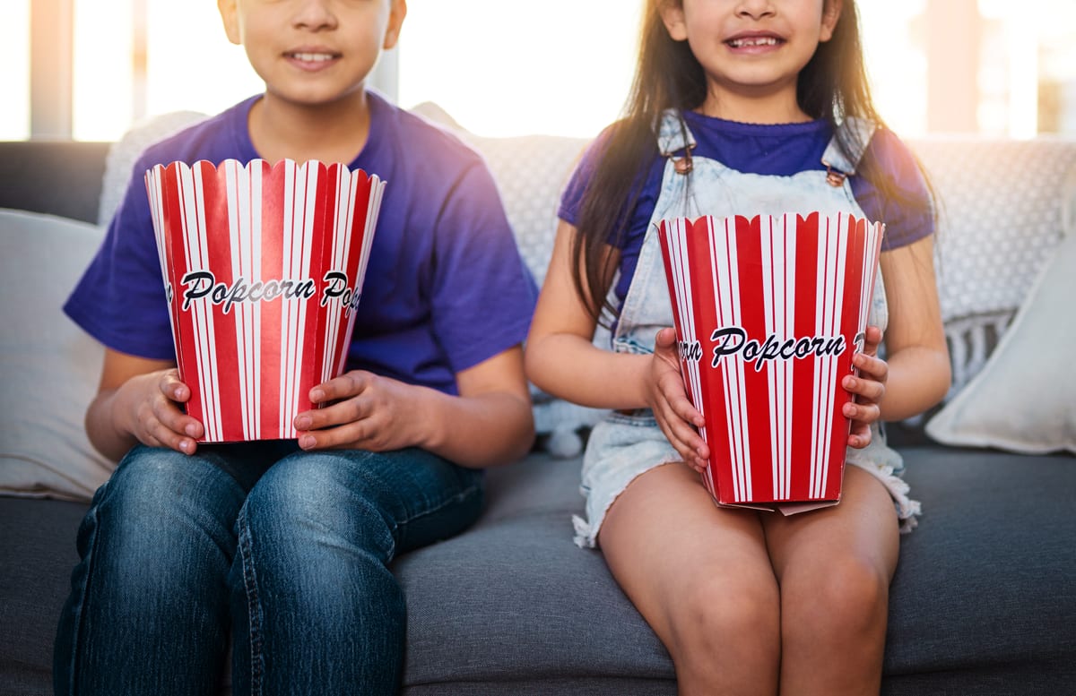 Popcorn Machine hire — young children enjoying popcorn at home on couch | Panda Party Hire Hire popcorn machine — young children enjoying popcorn at home on couch for parties and events in Johannesburg, Sandton and Randburg