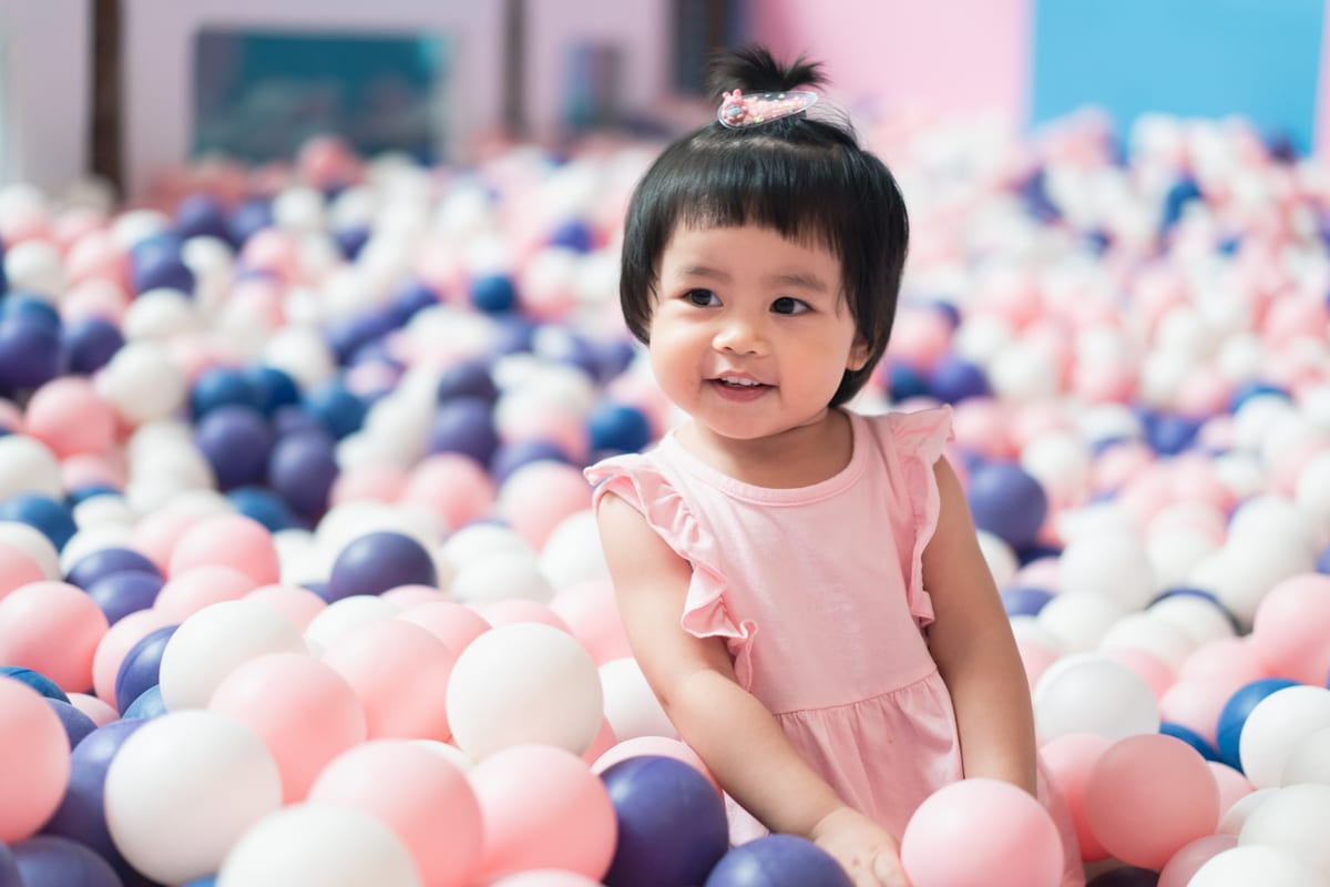 Hire soft play equipment — cute asian baby playing a lot of balls at the fun for parties and events in Johannesburg, Sandton and Randburg